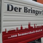Weißer Lieferwagen Mit Aufschrift &Quot;Der Bringer!&Quot;, Roter Stadtsilhouette Und Website-Adresse An Der Seite Auf Straße.