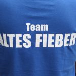 Rückansicht Eines Blauen T-Shirts Mit Weißem Aufdruck &Quot;Team Altes Fieber&Quot; Auf Dem Rücken.