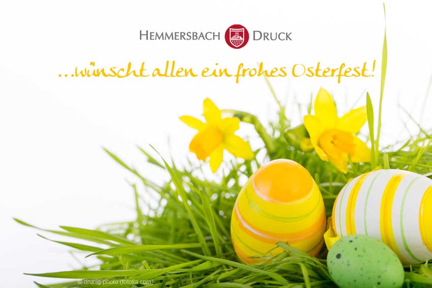 Gelbe Narzissen Und Bunte Ostereier Liegen Auf Grünem Gras, Im Hintergrund Steht Ein Froher Ostergruß Auf Deutsch.