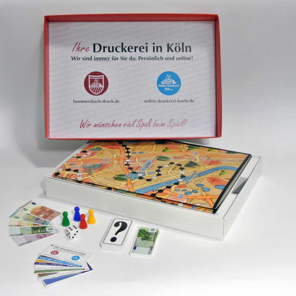 Geöffnete Brettspielschachtel Mit Spielbrett, Karten, Spielgeld, Würfeln Und Figuren; Deckel Zeigt Werbeanzeige.