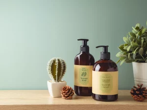 Braune Spenderflaschen Mit Nature Soap Etikett Neben Kaktus, Tannenzapfen Und Grüner Pflanze Auf Holzoberfläche – Druckerei Hemmersbach