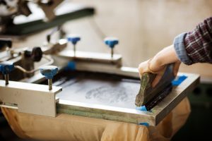 Manuelle Siebdruckarbeit Mit Rakel Auf Textil, Nahaufnahme Einer Hand Beim Druckprozess – Druckerei Hemmersbach