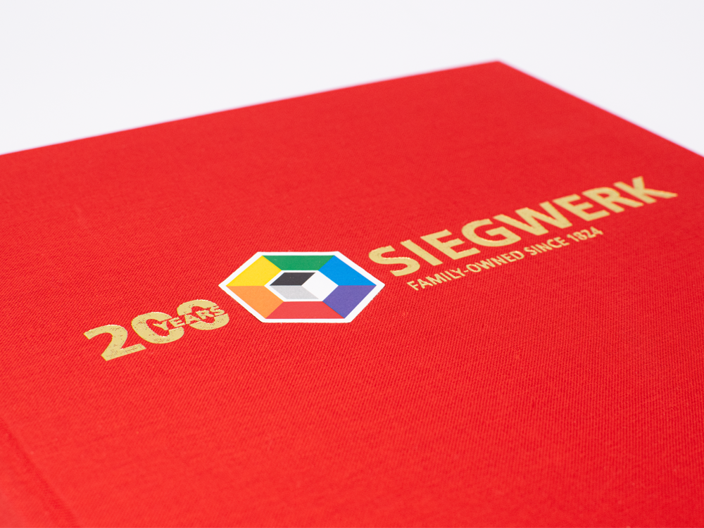 Buchdruck Rotes Buchcover Mit Goldener Prägung „200 Years Siegwerk – Family-Owned Since 1824“ Und Farbigem Logo – Druckerei Hemmersbach