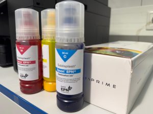 Drei Flaschen Epson Epn+ Sublisplash Sublimationstinte In Magenta, Gelb Und Cyan, Stehend Neben Einer Weißen Prime-Verpackung