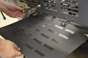Druckprozess Mit Heißfolienprägung Des „Lamoto“-Logos Auf Schwarzem Karton In Einer Druckmaschine