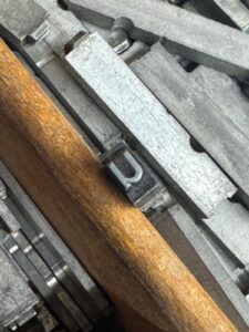 Metall-Buchdrucklettern Und Hölzerner Trenner Liegen Sortiert Für Den Druckereieinsatz Nebeneinander.