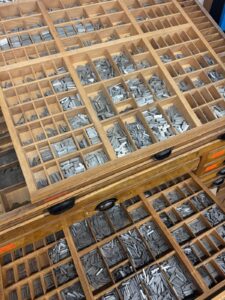 Holzschubladen Mit Sortiertem Metall-Letternsatz Bei Traditionellen Druckarbeiten In Einer Modernen Werkstatt.