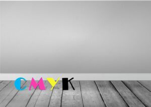 Buchstaben Cmyk In Cyan, Magenta, Gelb Und Schwarz Liegen Auf Holzboden Vor Einer Grauen Wand.
